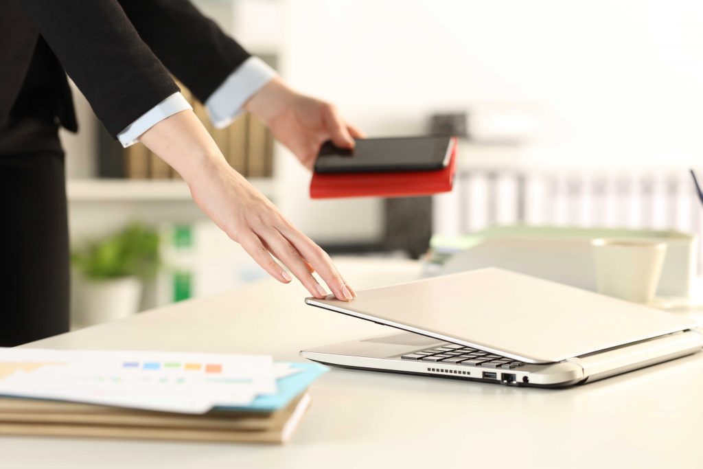 Executive hands leaving office closing laptop